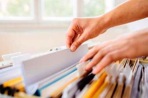 Person looking through an open filing cabinet to put a folder back in