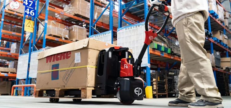 man using an electric pallet truck in a warehouse to move/transport heavy materials and products.